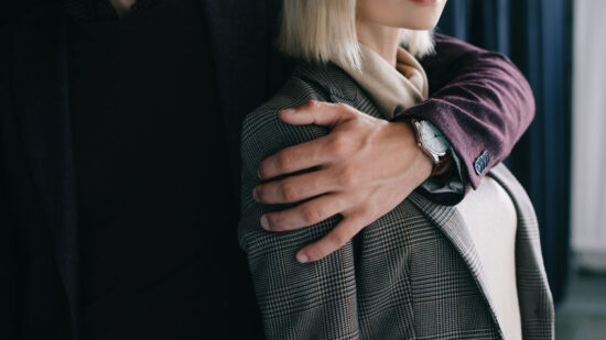 cropped view of young man embracing blonde girl near curtain